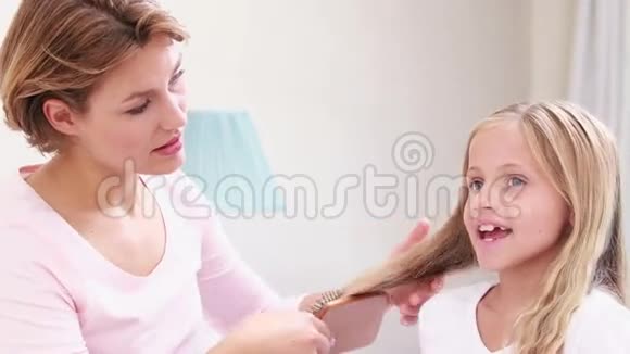 微笑的母亲梳着女儿的头发视频的预览图