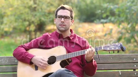 男子在公园弹声吉他和唱歌视频的预览图