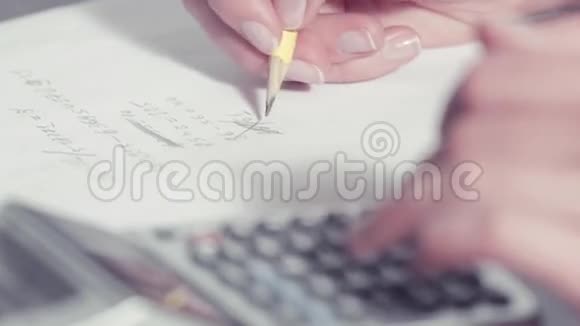 女人用铅笔写字用计算器打字视频的预览图