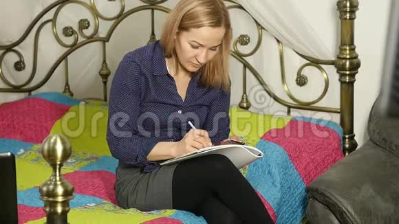 漂亮的女人在她房间里的一张床上学习笔记本电脑网上教育视频的预览图