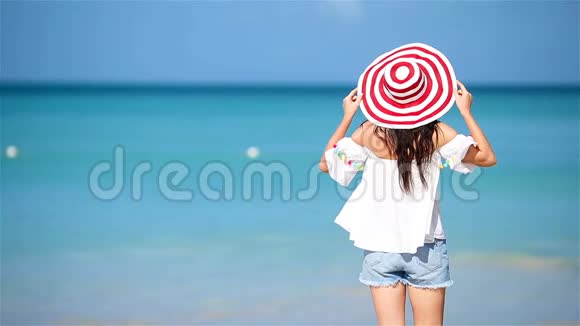 在白沙热带海滩上的年轻美女带帽子的白种人女孩的后景视频的预览图