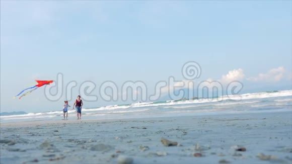 快乐的奶奶带着孩子玩着放风筝一家人在热带海洋的沙滩上玩耍视频的预览图