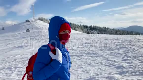 孤独的旅游女孩沿着白雪覆盖的山顶散步晴朗的霜冻天气视频的预览图