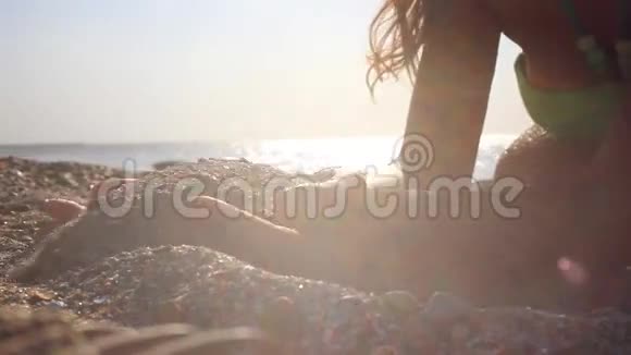 女人的手在阳光下在沙滩上撒沙视频的预览图