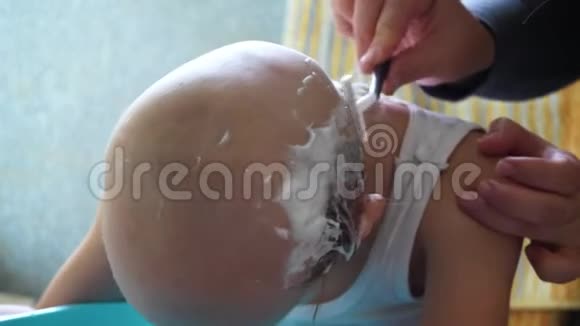 年轻的母亲用剃刀剃掉金发男孩的头以防止椎弓根良好的家庭传统视频的预览图