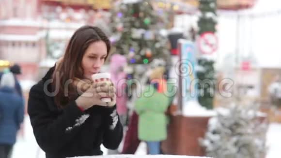 美丽的年轻女子在圣诞集市上喝热茶视频的预览图