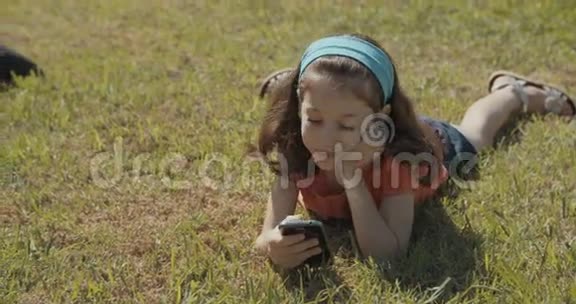 小女孩在户外草地上用手机视频的预览图