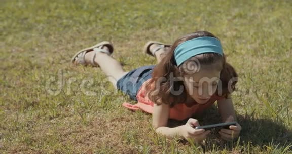 小女孩在户外草地上用手机视频的预览图
