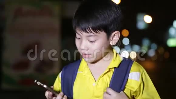 亚洲小孩在夜间灯光背景下玩智能手机视频的预览图