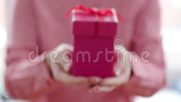 在女人手里用红丝带把粉色礼品盒收起来视频的预览图