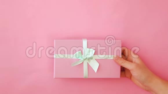 简单设计女性手握粉色礼品盒隔离粉彩贴色彩缤纷时尚背景视频的预览图