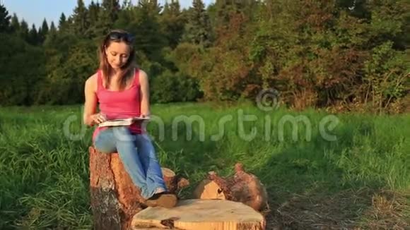 年轻女子坐在公园里看书视频的预览图