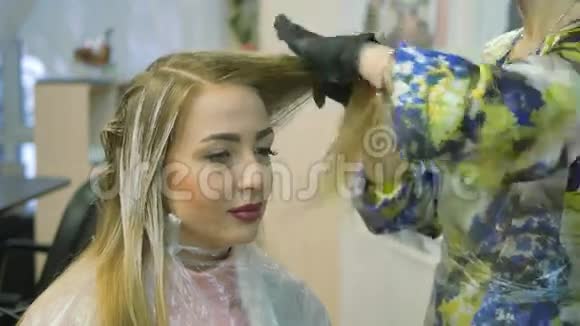 理发师染发剂金发女郎坐在美容院理发师染发视频的预览图