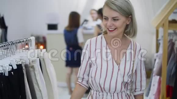 购物女孩服装店里一个漂亮女人的肖像在服装店里红唇的金发女郎视频的预览图
