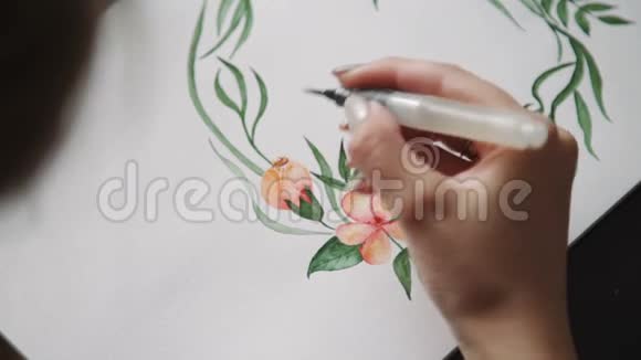 一位年轻的女艺术家用水彩画画一朵水刷花一个绿叶的花环近点视频的预览图