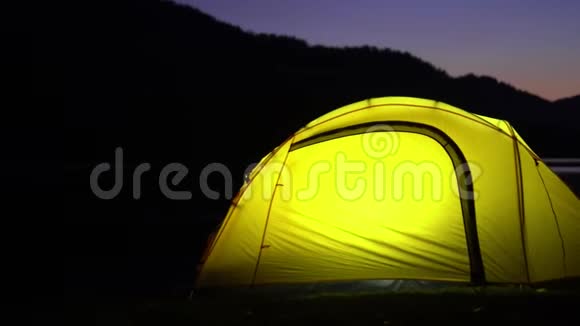 黄色帐篷在山湖畔花费晚安在帐篷里光线燃烧视频的预览图