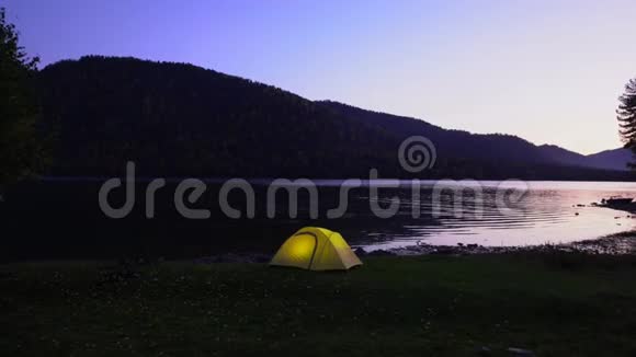 黄色帐篷在山湖畔花费晚安在帐篷里光线燃烧视频的预览图