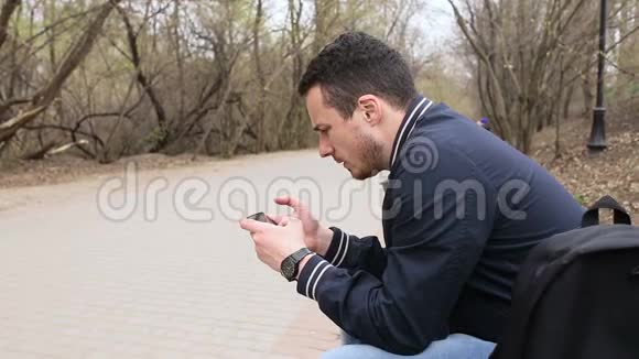 年轻人在公园玩触摸屏电话视频的预览图