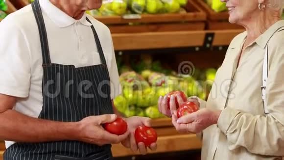 高级顾客和工人讨论杂货店的蔬菜视频的预览图
