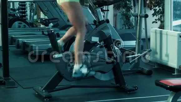 运动的女人在健身房骑着一辆静止的自行车在模拟器上踏板视频的预览图