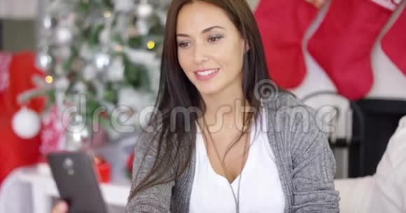 微笑的年轻女人在查看圣诞信息视频的预览图