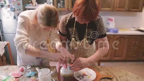 糖果女人和女孩准备复活节蛋糕用五颜六色的装饰装饰女人用自己的蛋糕准备视频的预览图