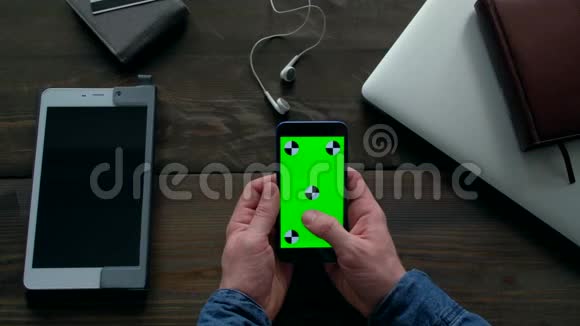 男人的手使用智能手机绿色屏幕在木桌上视频的预览图