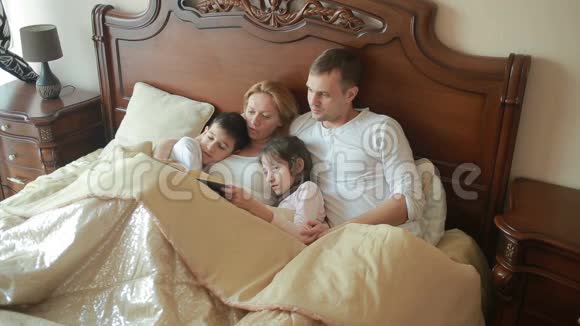 快乐的一家人在床上大声读一本书视频的预览图