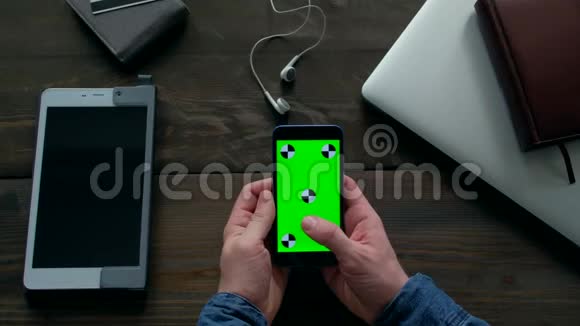 男人的手使用智能手机绿色屏幕在木桌上视频的预览图