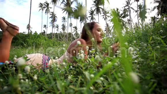 年轻美丽的微笑女人躺在草坪上视频的预览图