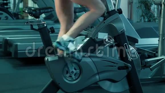 运动女性在健身房的固定自行车上骑模拟器视频的预览图