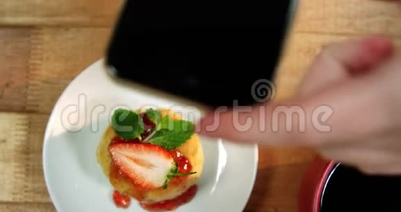 女人在手机上拍照吃甜食视频的预览图