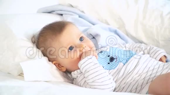有着蓝色大眼睛和金发的婴儿在床上视频的预览图