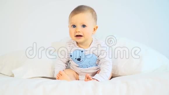有着蓝色大眼睛和金发的婴儿在床上视频的预览图
