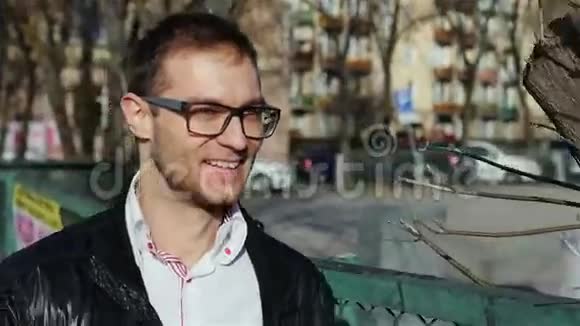 戴眼镜的年轻人在城市街道上行走的肖像视频的预览图