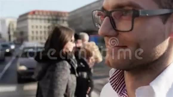 戴眼镜的年轻人在城市街道上行走的肖像视频的预览图