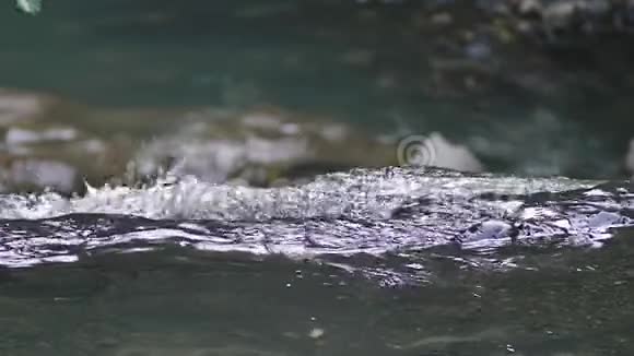 特写镜头落石山上的瀑布水流迅速下坠生成白色起泡泡沫石头瀑布视频的预览图