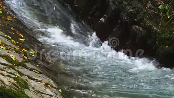 特写镜头落石山上的瀑布水流迅速下坠生成白色起泡泡沫石头瀑布视频的预览图