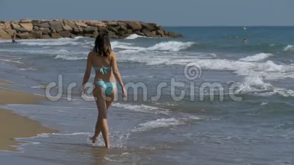 少女缓慢地沿着海岸海滩漫步视频的预览图
