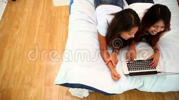 有魅力的姐妹们躺在床上用笔记本电脑视频的预览图
