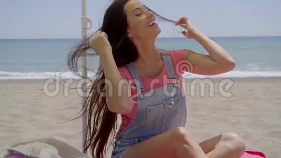 美丽的女人坐在沙滩的阴凉处视频的预览图