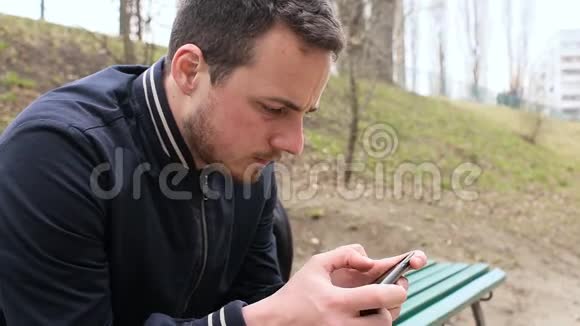 年轻人在公园玩触摸屏电话视频的预览图