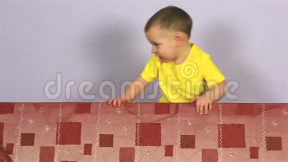 快乐快乐的小男孩在沙发上玩耍和跳跃视频的预览图
