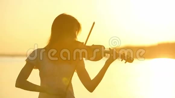 日落时分女小提琴手在湖边拉小提琴视频的预览图