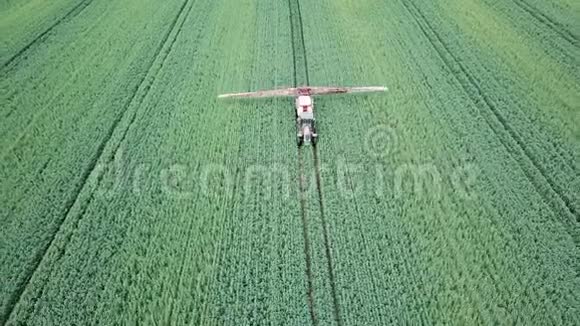 空中观景农业机械在绿色的大田野上喷洒化学物质视频的预览图