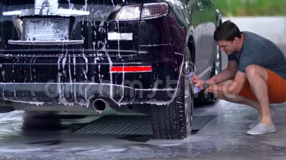 年轻人在清洗他的黑色轿车视频的预览图