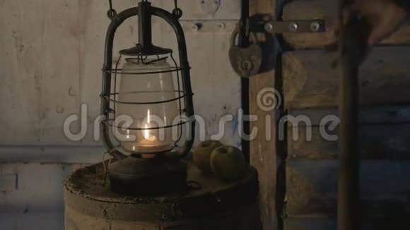 晚上农夫在一张有苹果的木桌上放了蜡烛的古玩灯带来了一盏灯和一盏灯视频的预览图