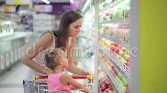 在超市购物时选择水果的女人和小女孩视频的预览图