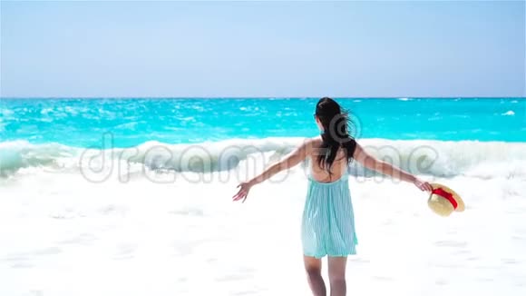 在白沙热带海滩上的年轻美女带帽子背景的白种人女孩的背面海景视频的预览图