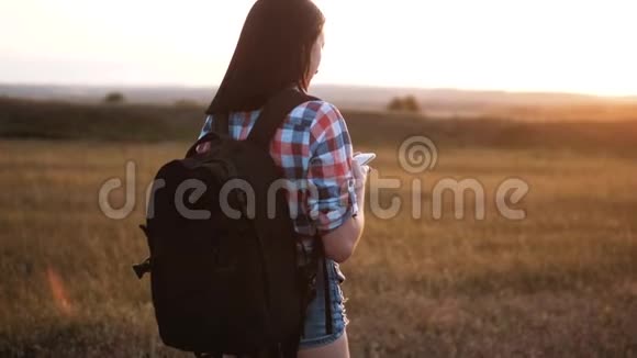 hipsterhiker的剪影女孩走着流浪的背包在手机上搜索位置导航视频的预览图